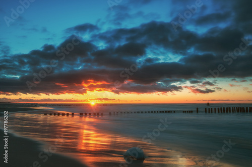 Sunrise  sunset of a beautiful winter landscape with frozen wooden breakwater. Concept holidays and travel