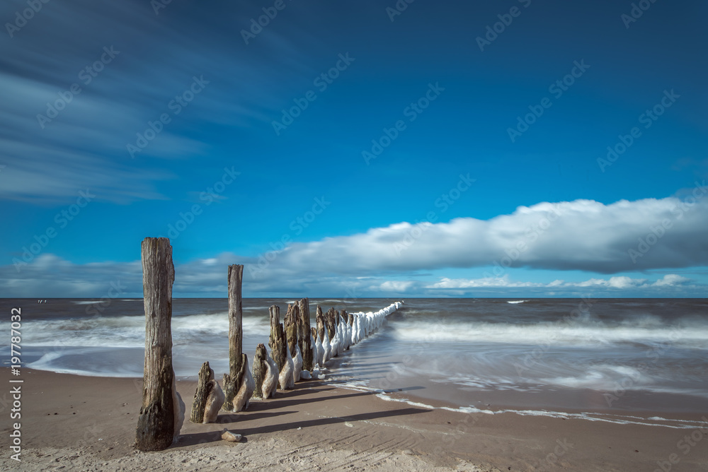 Long exposure of a beautiful winter landscape with frozen wooden breakwater. Concept holidays and travel Long exposure of a beautiful winter landscape with frozen wooden breakwater. Concept holidays and travel