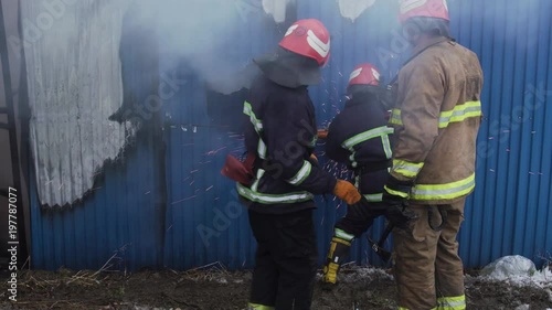 Market with carpets is on fire. Fireman gworking with chainsaw and the axe photo