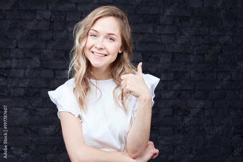 That's way all better. Cheerful enthusiastic beautiful young Caucasian woman with wavy blond hair showing thumb up gesture to camera, expression like and approval of idea or project, smiling broadly. That's way all better. Cheerful enthusiastic beautiful young Caucasian woman with wavy blond hair showing thumb up gesture to camera, expression like and approval of idea or project, smiling broadly.