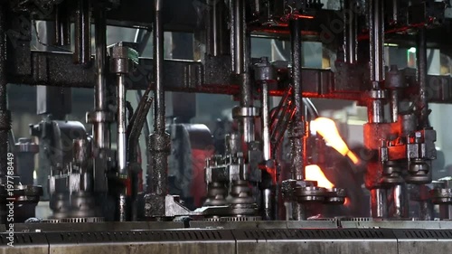 Hot glass is fed from the oven to the glass bottle making machine. Machine in the glass factory produces glass bottles Automated Production Line of Bottle In Factory. Ambient sound at factory. photo