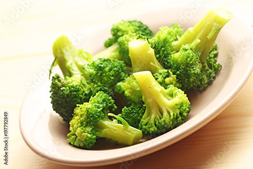 Green broccoli cabbage in plate on a wood background