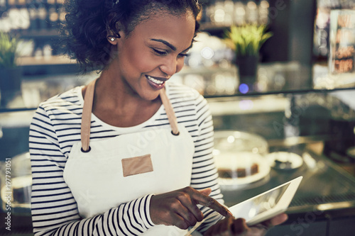 Foto Smiling African entrepreneur using a tablet in her trendy cafe