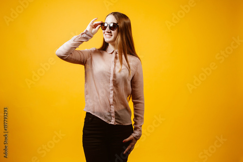 Picture of happy young woman standing isolated over yellow background.
