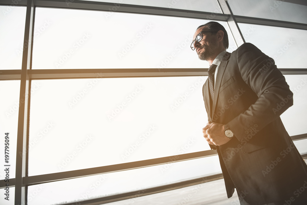 Low angle of calm confident middle aged man standing near large window.  Copy space in left side Stock Photo | Adobe Stock