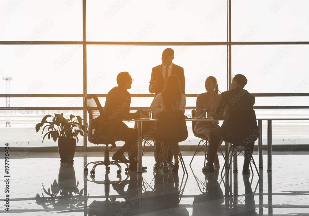 Group of managers sitting in the office and listening to discourse of their partner. Panoramic window on background Group of managers sitting in the office and listening to discourse of their partner. Panoramic window on background