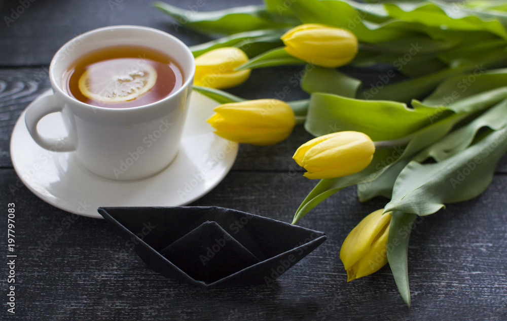 background with black ship, cap of tea and tulips (close up and horizontally) background with black ship, cap of tea and tulips (close up and horizontally)