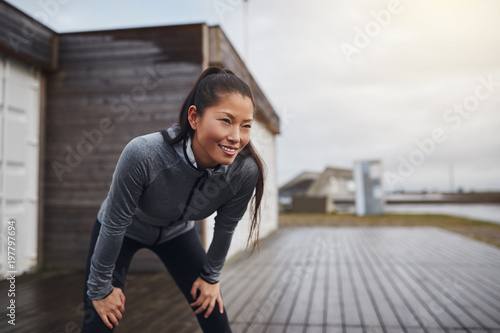 Fotografie Smiling young Asian woman taking a break while out jogging