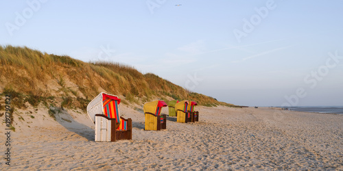 Foehr / Germany: Colorful empty hooded beach-chairs at Goting beach on the south coast of the Frisian island in the deep November afternoon sun