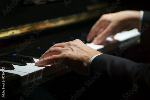 Fotografiet Professional musician pianist hands on piano keys of a classic piano in the dark