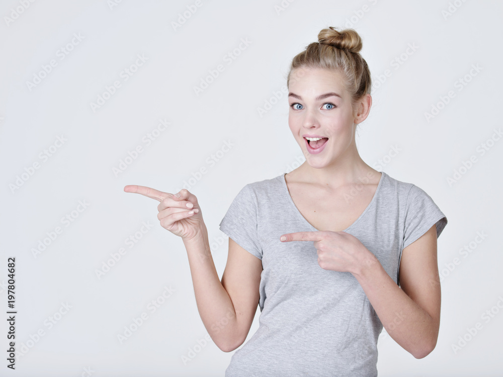 Smiling pretty woman pointing finger away