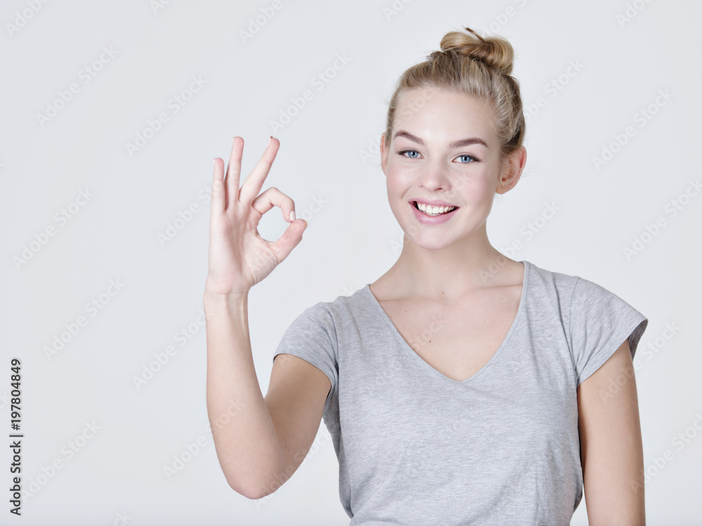 Beautiful young happy woman shows okay sign