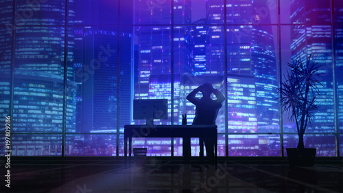 Silhouette of a man working late in the office at the computer