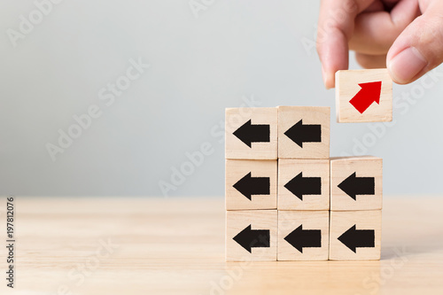 Fotografie Hand picked wooden block with red arrow facing the opposite direction black arro