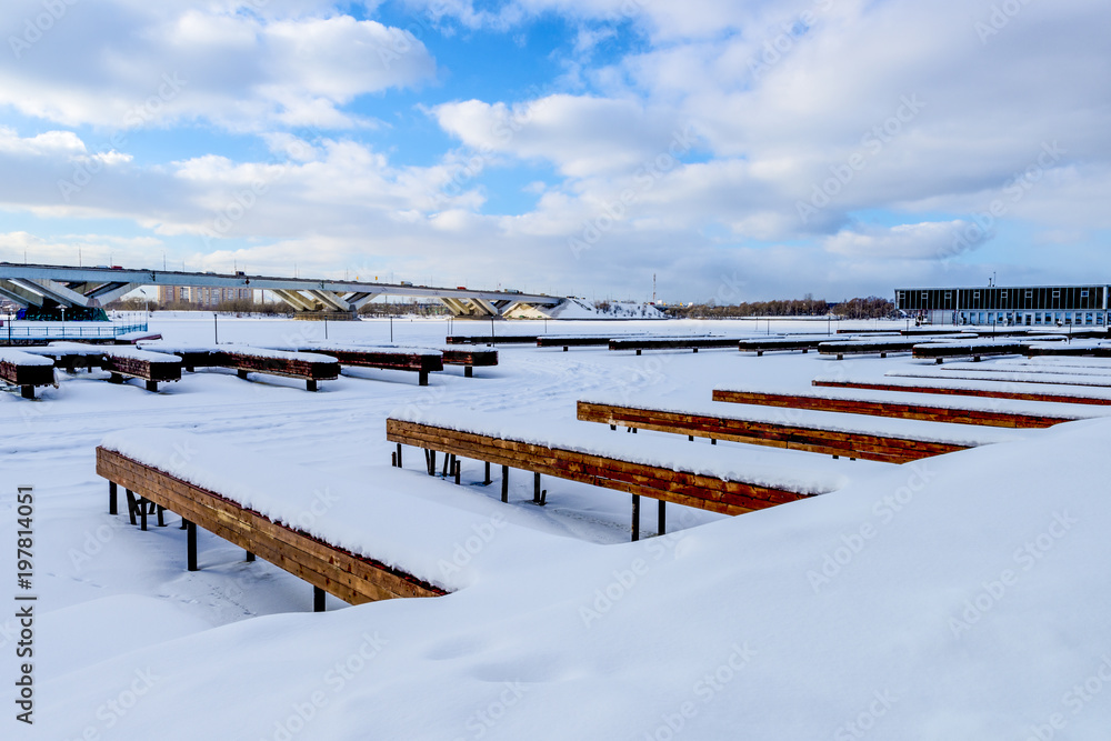 The frozen pond in Moscow and wooden berths for yachts in winter covered with snow
