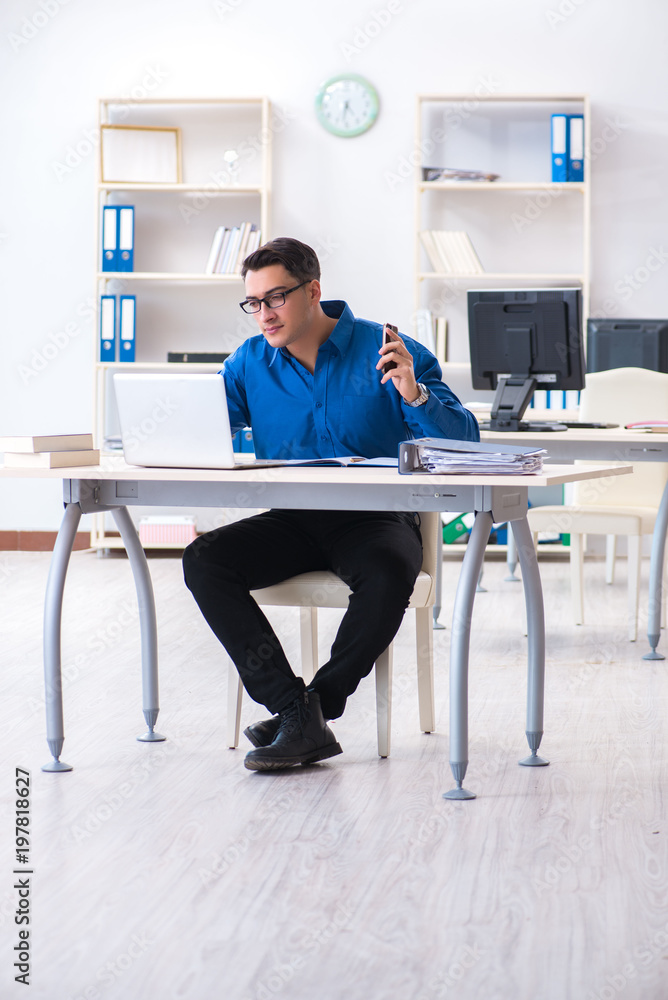 Handsome businessman employee sitting at his desk in office Handsome businessman employee sitting at his desk in office