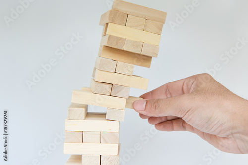 Man hand move out the block from falling tumbling tower