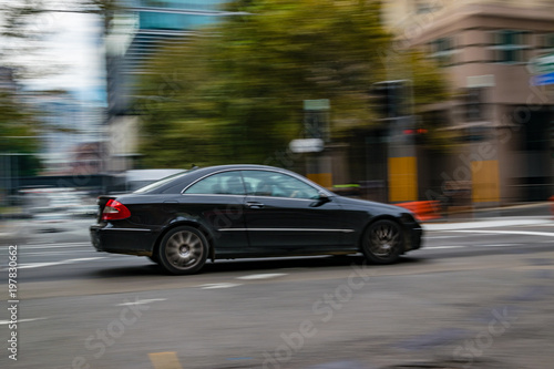 Black car in motion on the road, Sydney, Australia. Car moving on the road, blurred buildings in background.