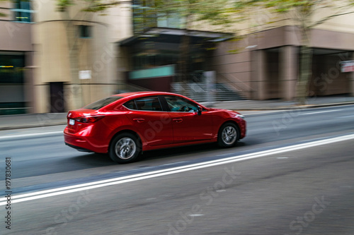 Red car in motion on the road, Sydney, Australia. Car moving on the road, blurred buildings in background. photo