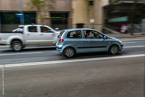 Cars in motion on the road, Sydney, Australia. Cars moving on the road, blurred buildings in background.