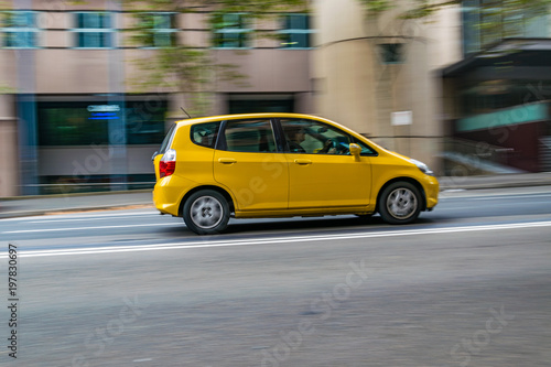 Yellow car in motion on the road, Sydney, Australia. Car moving on the road, blurred buildings in background.