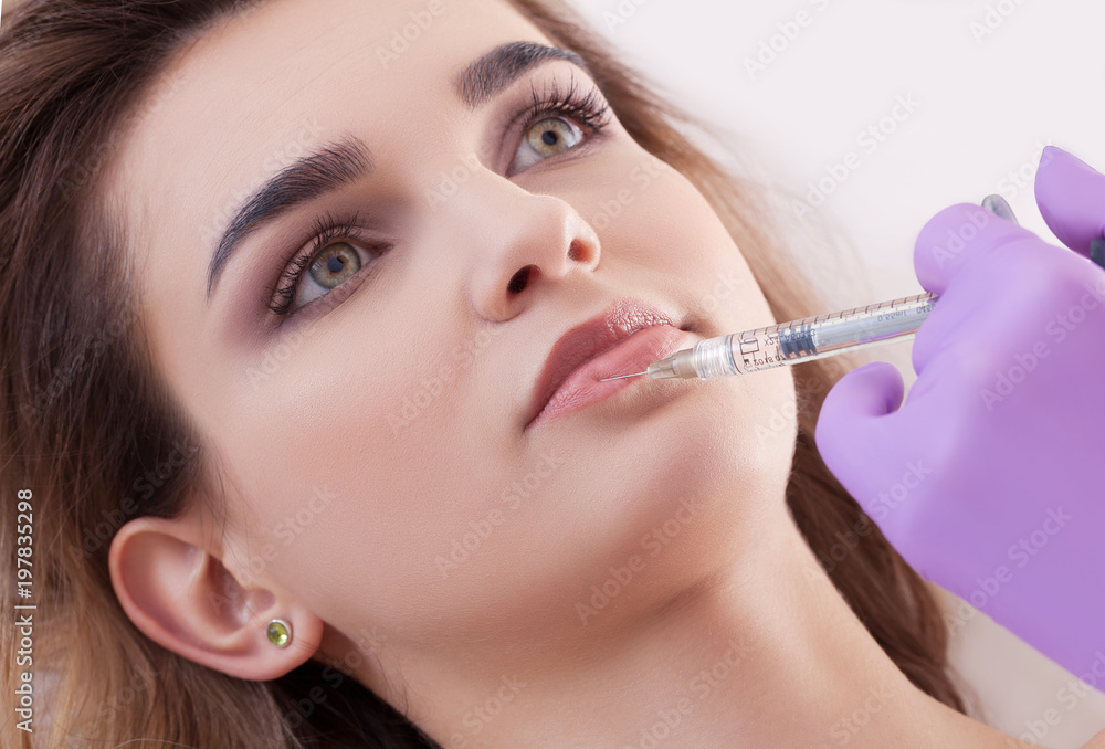 woman receiving a botox injection in her lips, close up. woman receiving a botox injection in her lips, close up.