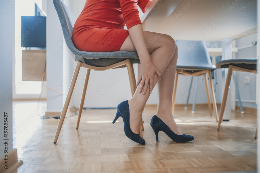 Fotka „attractive young female office worker finished work back to home  sitting and relaxing and feeling feet painful take off high heel shoes  using hand massage.“ ze služby Stock | Adobe Stock