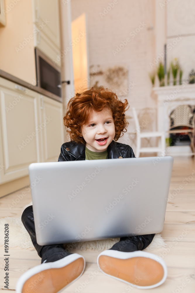Little redhead boy uses a laptop Little redhead boy uses a laptop