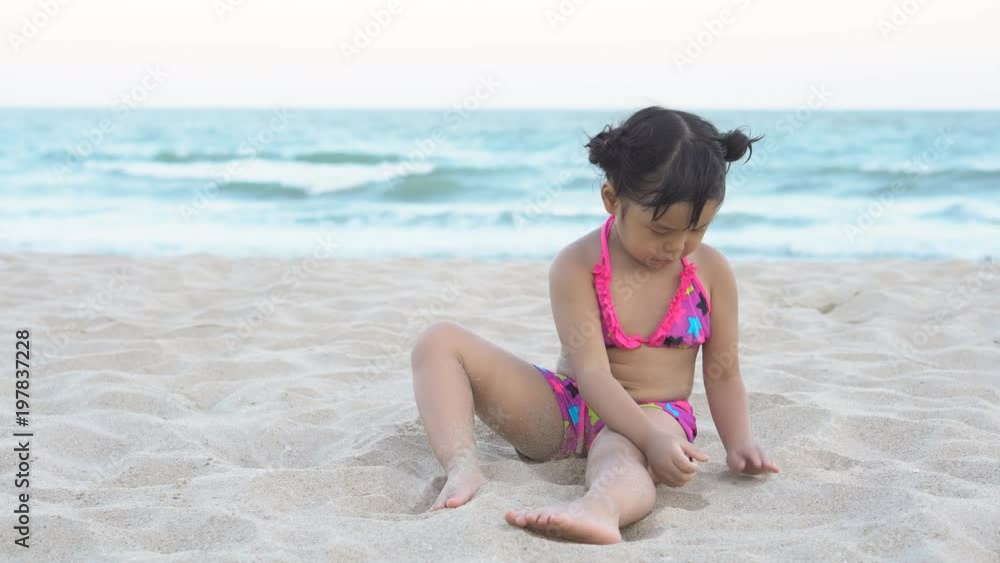Asian children cute or kid girl sit on beach or blue sea and ...