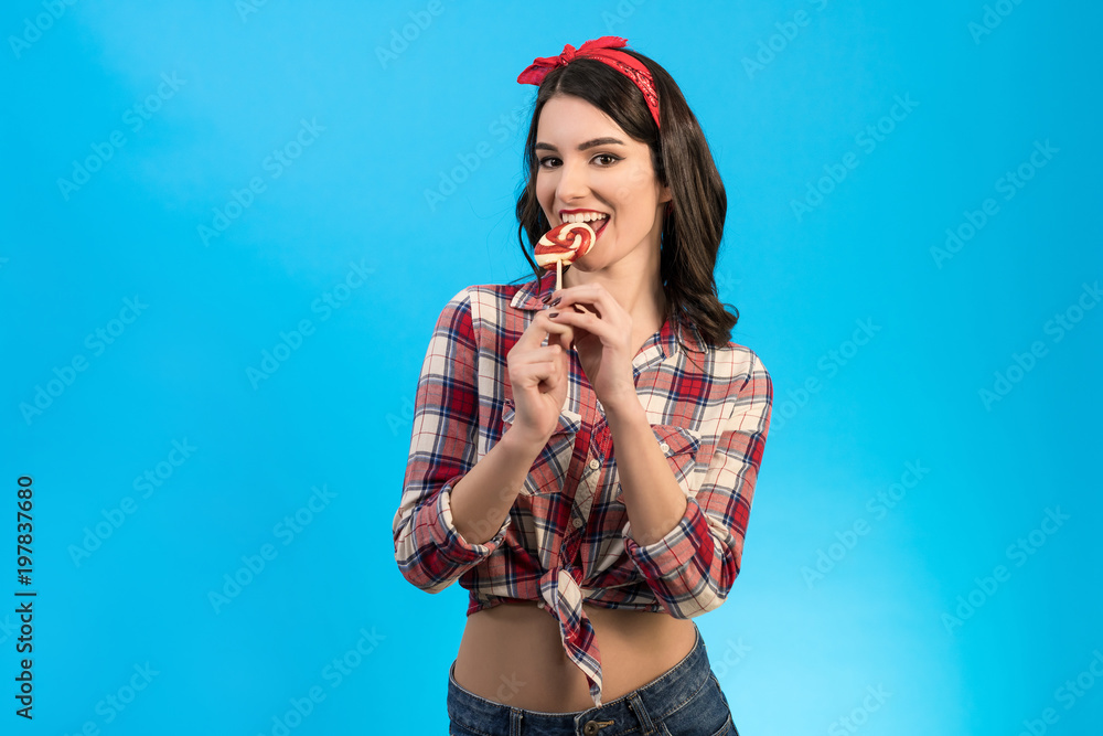 The happy woman eating a candy on the blue background The happy woman eating a candy on the blue background