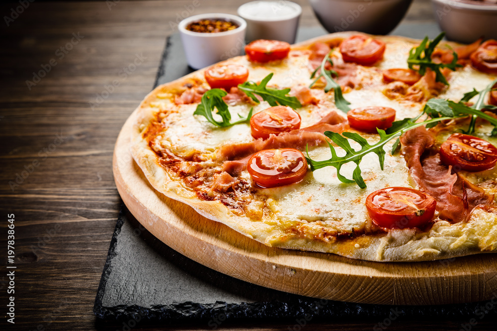 Pizza with ham and vegetables on wooden table Pizza with ham and vegetables on wooden table