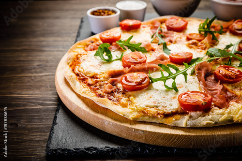 Pizza with ham and vegetables on wooden table