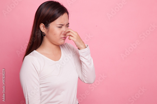 Young Asian woman holding her nose because of a bad smell.