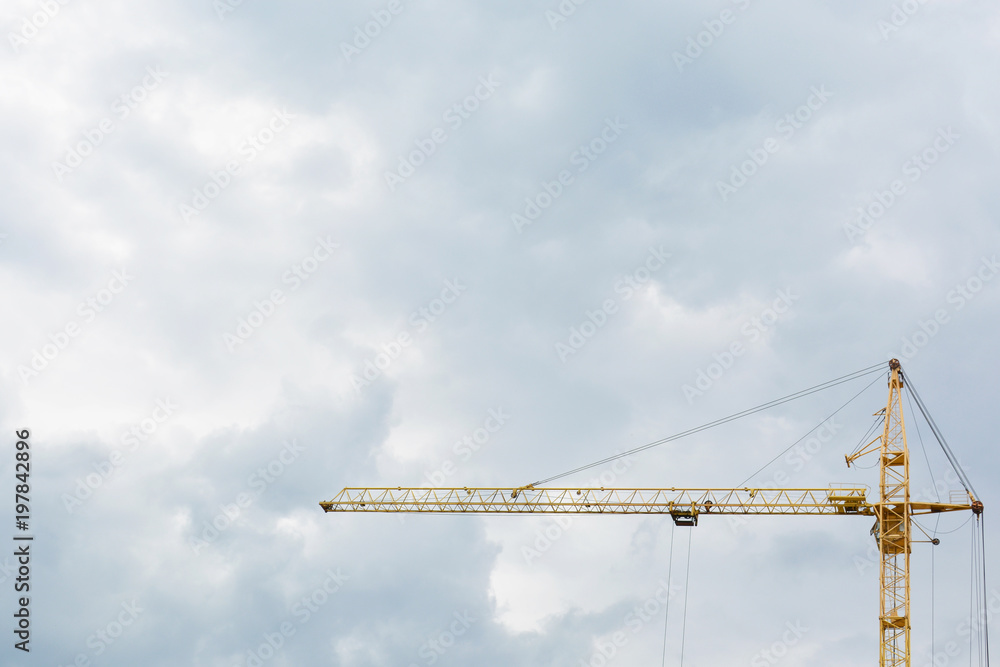 A construction yellow crane against the background of a dark sky. A construction yellow crane against the background of a dark sky.