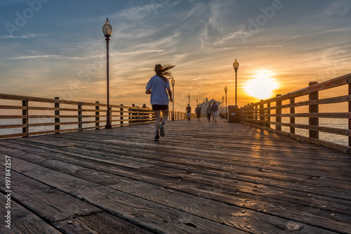 A girl running on Oceanside pier at sunset, California