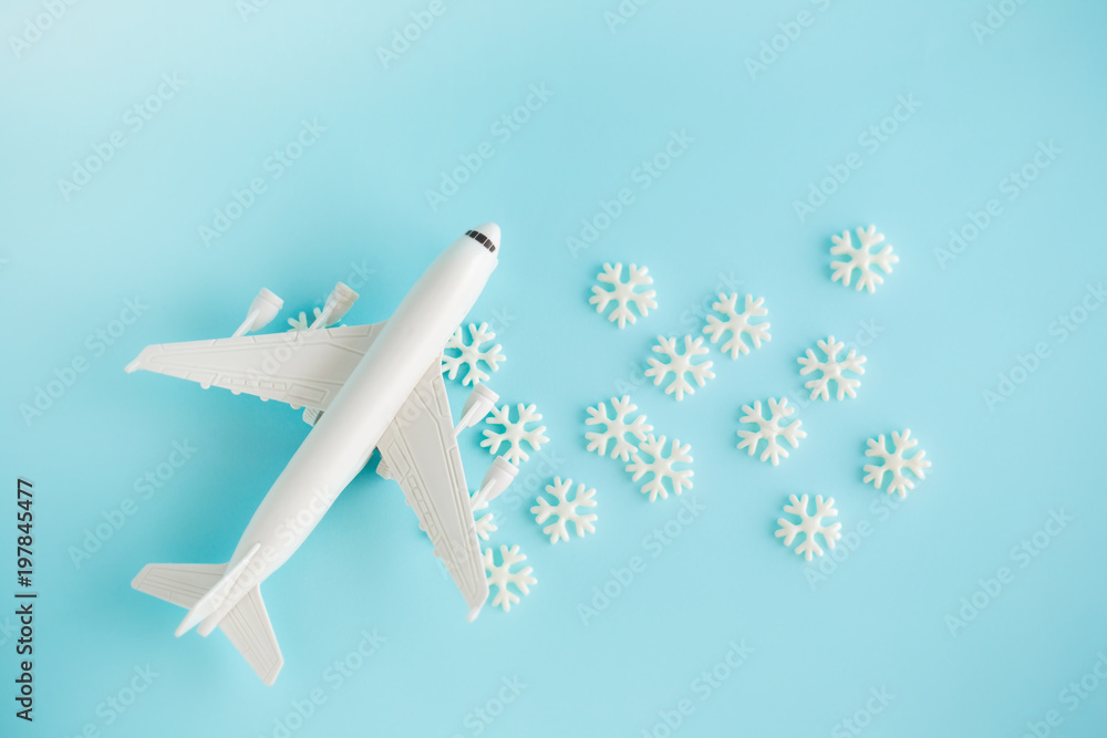 Fototapeta premium Plastic toy airplane and white snowflakes on Blue sky Background.