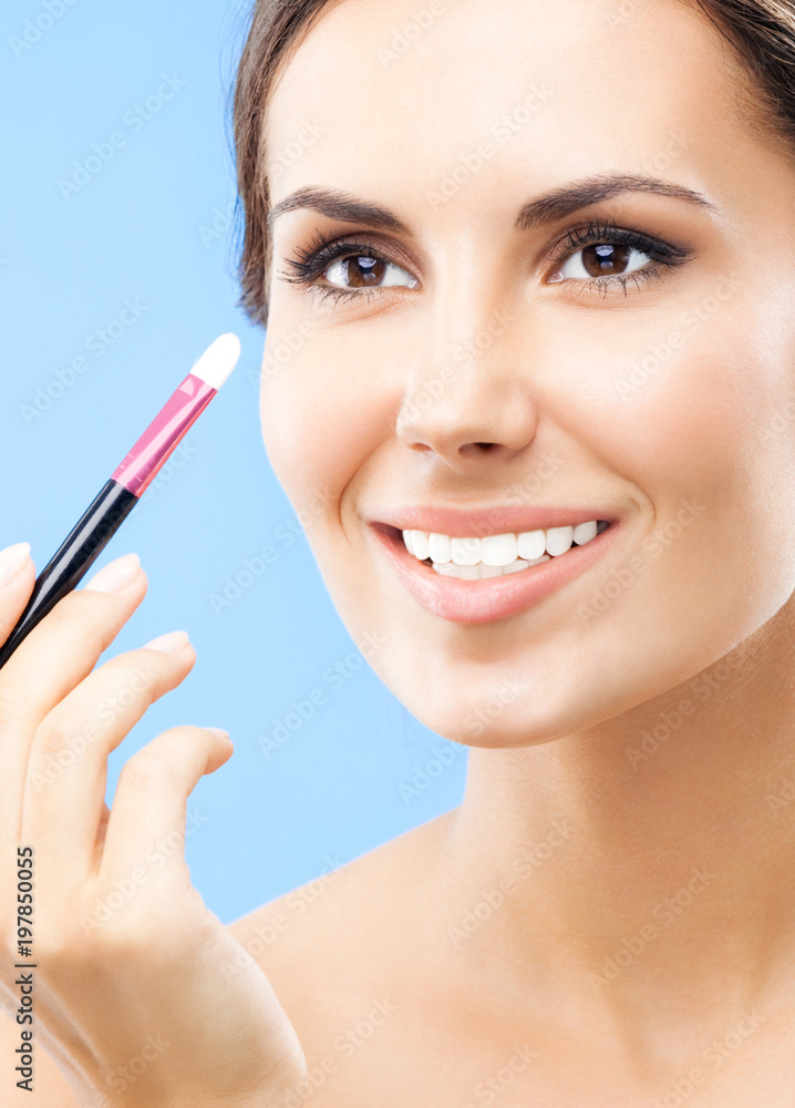 Woman with cosmetics brush, on blue