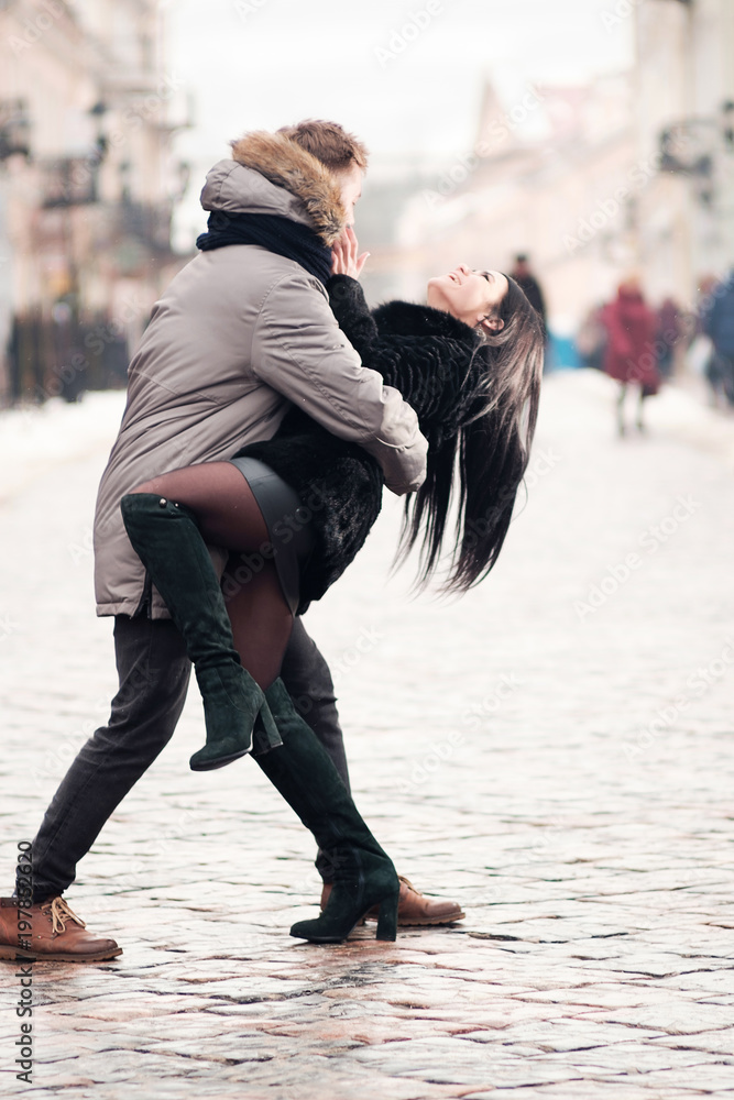 young happy couple hug each other while walking in the street of town in  winter under snowfall and smiling, man hug girl in funny manner, both  laughing Stock Photo | Adobe Stock
