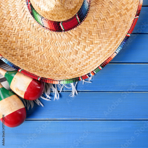 Mexico cinco de mayo background border square format with sombrero straw hat traditional rug or blanket and maracas on an old blue wood background fiesta carnival photo
