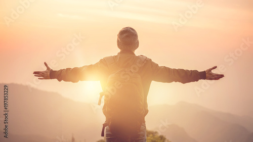Fotografie Carefree Happy Man Enjoying Nature on top of mountain cliff with morning sunrise outdoor, Freedom concept