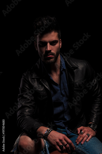 seated fashion man in leather jacket resting elbow on knee © Viorel Sima