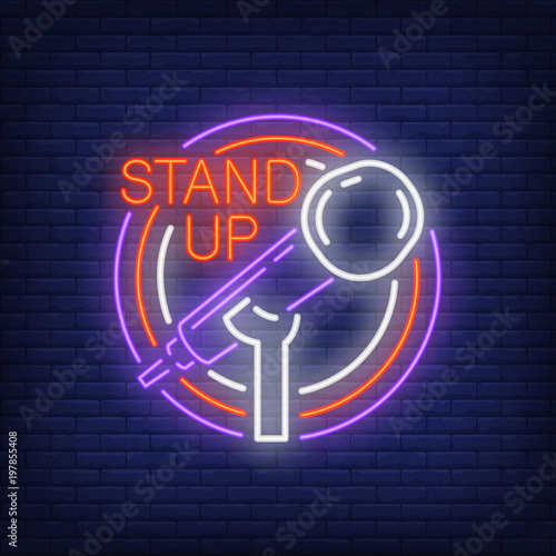 Stand up neon sign. Stand microphone in round frame on brick wall background. Night bright advertisement. Vector illustration in neon style for comedy show