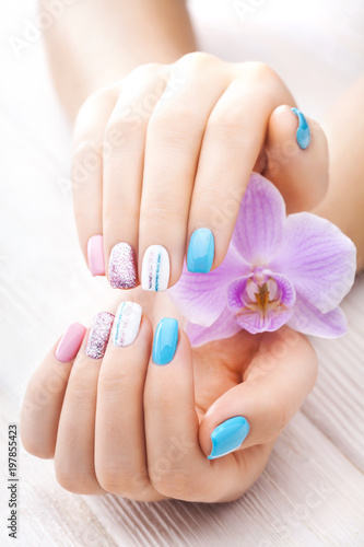beautiful colored manicure with orchid, candle and towel on the white wooden table.
