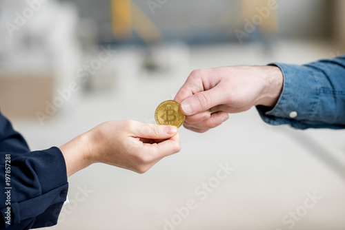 Businesswoman giving a cryptocoin to builder for the work at the construction site. Close-up view focused on the hands