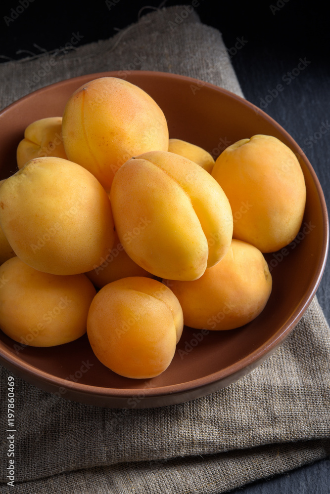 Sweet apricots in bowl on linen and black slate stone Sweet apricots in bowl on linen and black slate stone