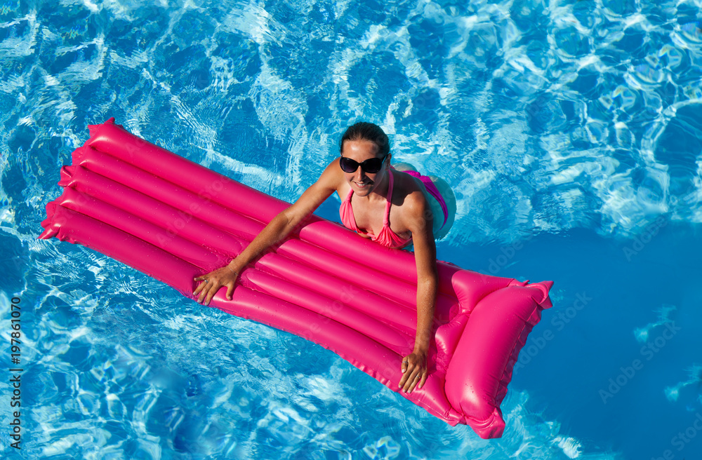 Happy woman swimming with pink inflatable mattress