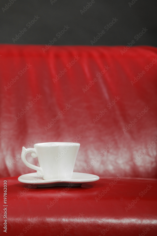 Small white tea of coffee cup on red sofa
