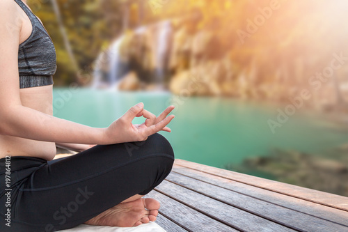 A young woman doing yoga on wooden deck next to a river in national park