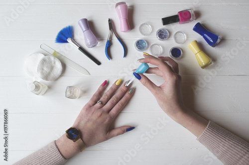 A woman painting her nails. Tools for manicure on a white wooden table.