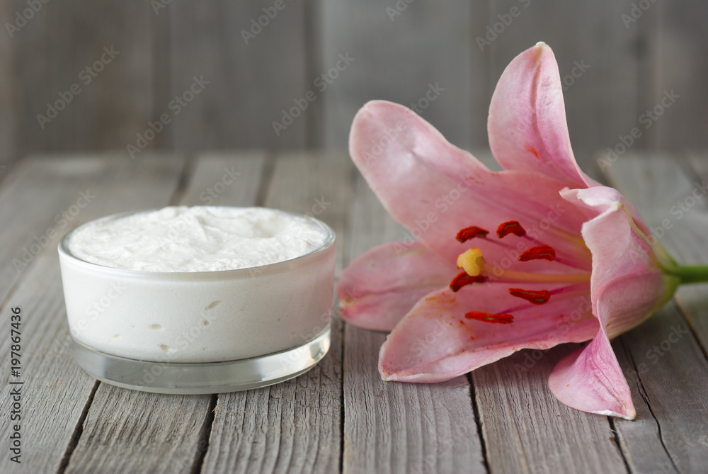 Moisturizer and lily flower on weathered wooden Moisturizer and lily flower on weathered wooden